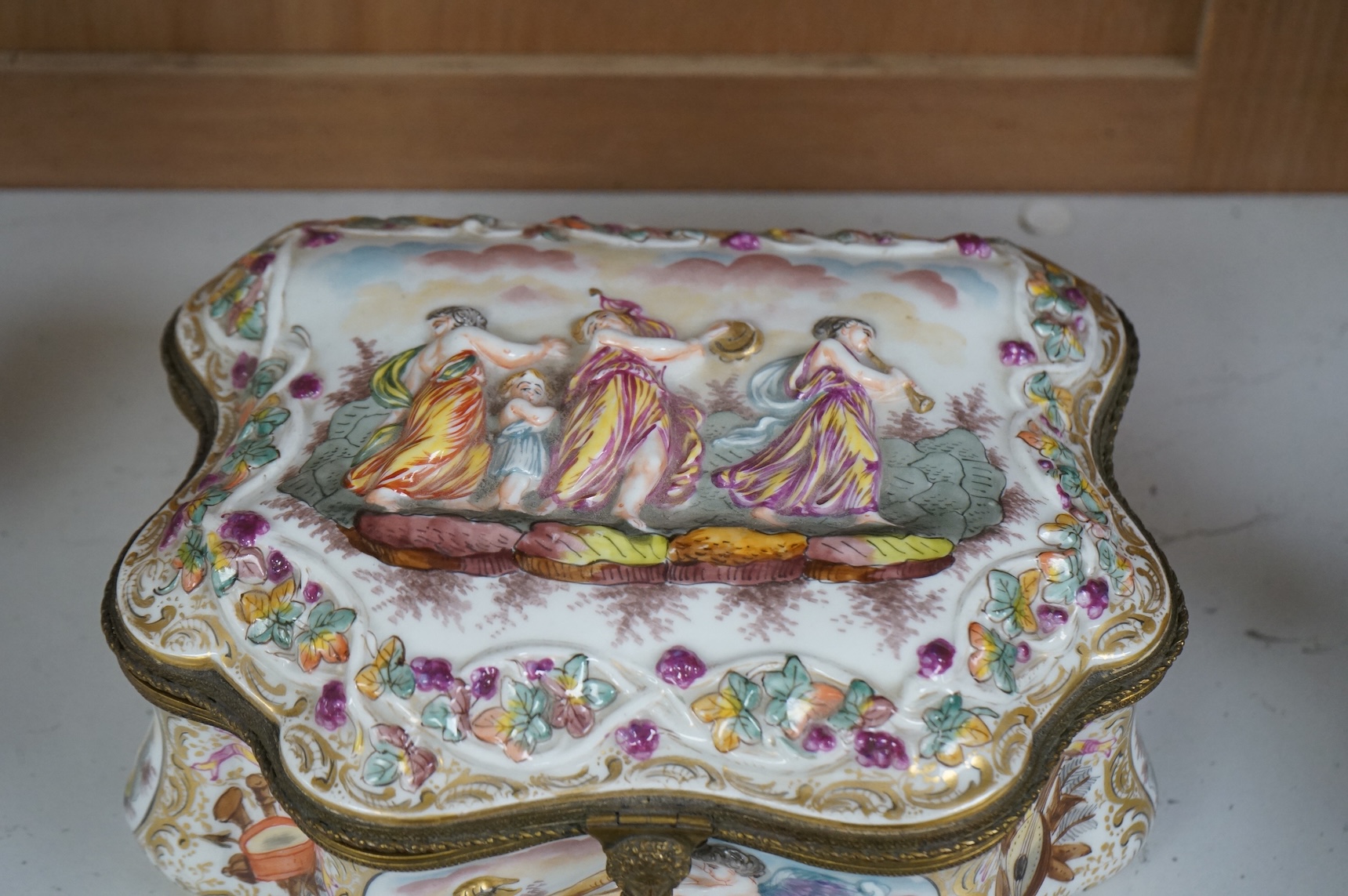 An ornate Neapolitan Capodimonte porcelain box with gilt mounts, 22cm wide, 11cm high